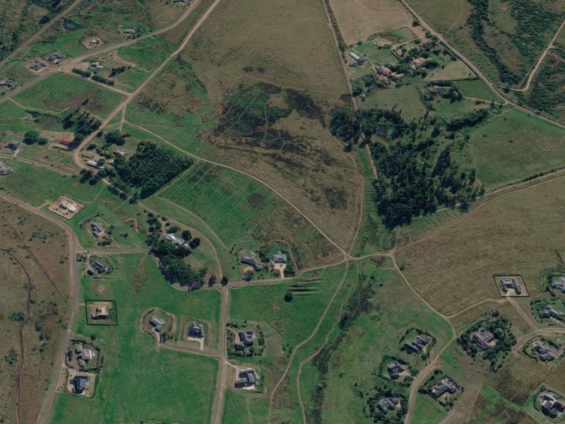 An aerial view of a residential development area featuring multiple plots of vacant land and established rural road infrastructure.