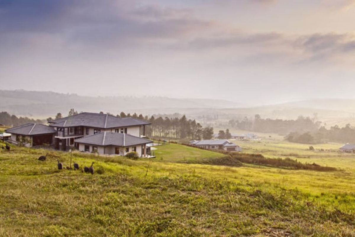 An elevated view of a residential property set within a sprawling, scenic landscape with rolling hills and natural vegetation.