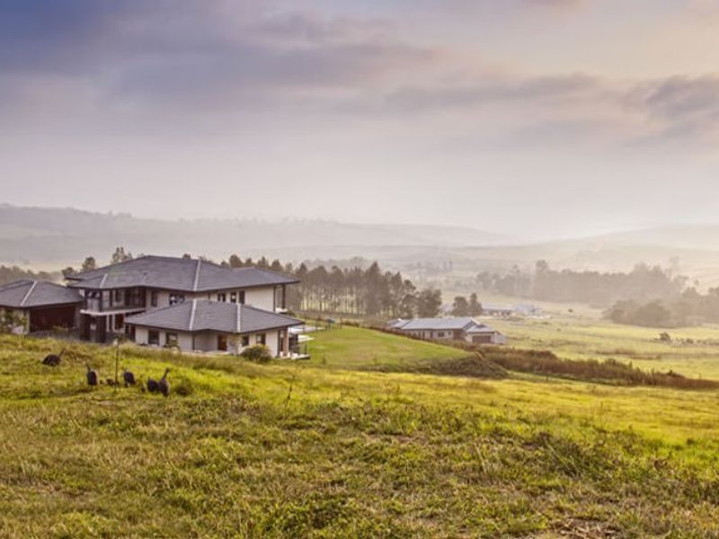 An elevated view of a residential property set within a sprawling, scenic landscape with rolling hills and natural vegetation.