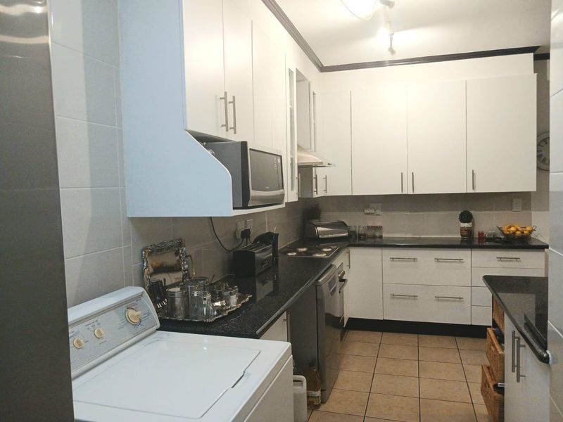 A functional kitchen featuring white cabinetry, dark granite countertops, tiled backsplash, and integrated appliances, offering a clean and practical workspace.