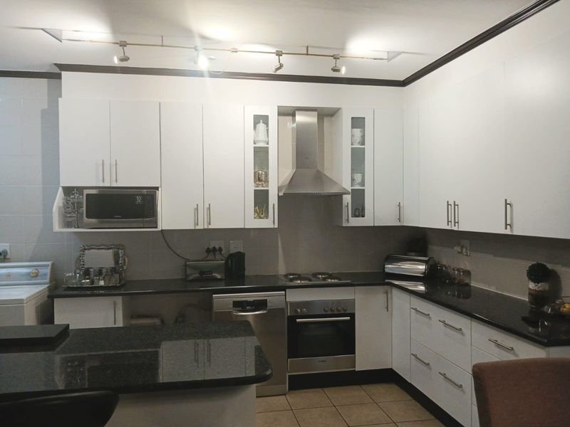 Modern kitchen featuring white cabinetry, dark granite countertops, stainless steel appliances, and functional track lighting, providing a clean and efficient workspace.