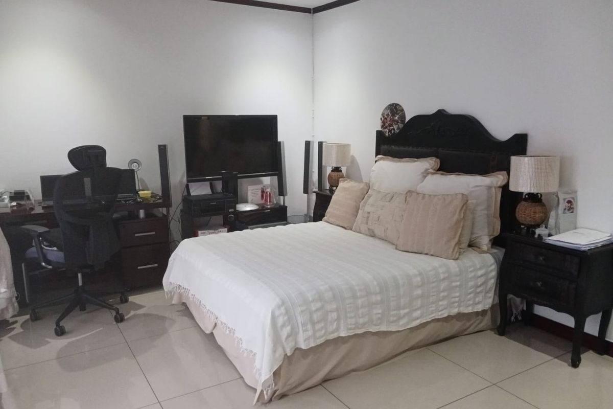 A functional bedroom featuring tiled flooring and recessed downlighting, providing a neutral base for personal styling.