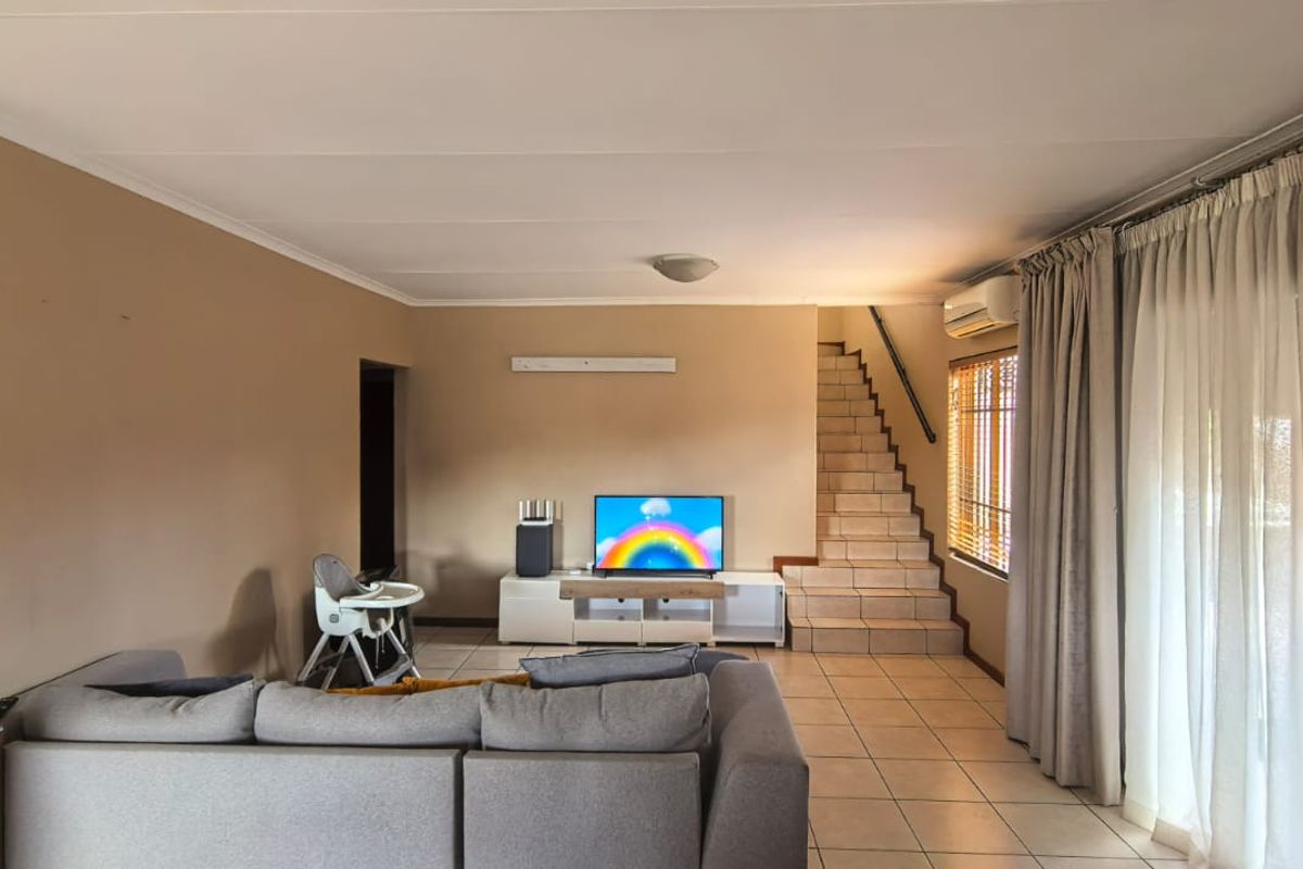 Spacious living room featuring tiled flooring, a staircase leading to the upper level, and large sliding doors providing access to the exterior.