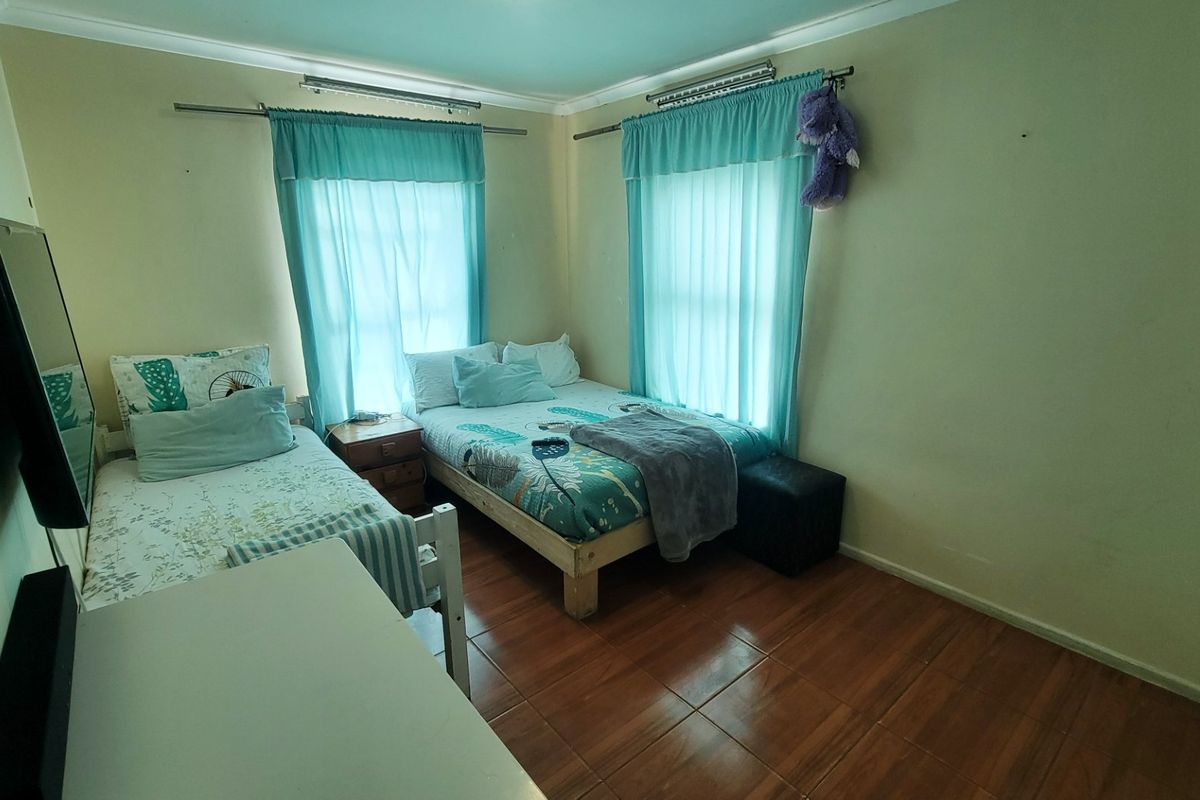 A functional bedroom featuring tiled flooring, dual windows with curtain rods, and cove cornice detailing.