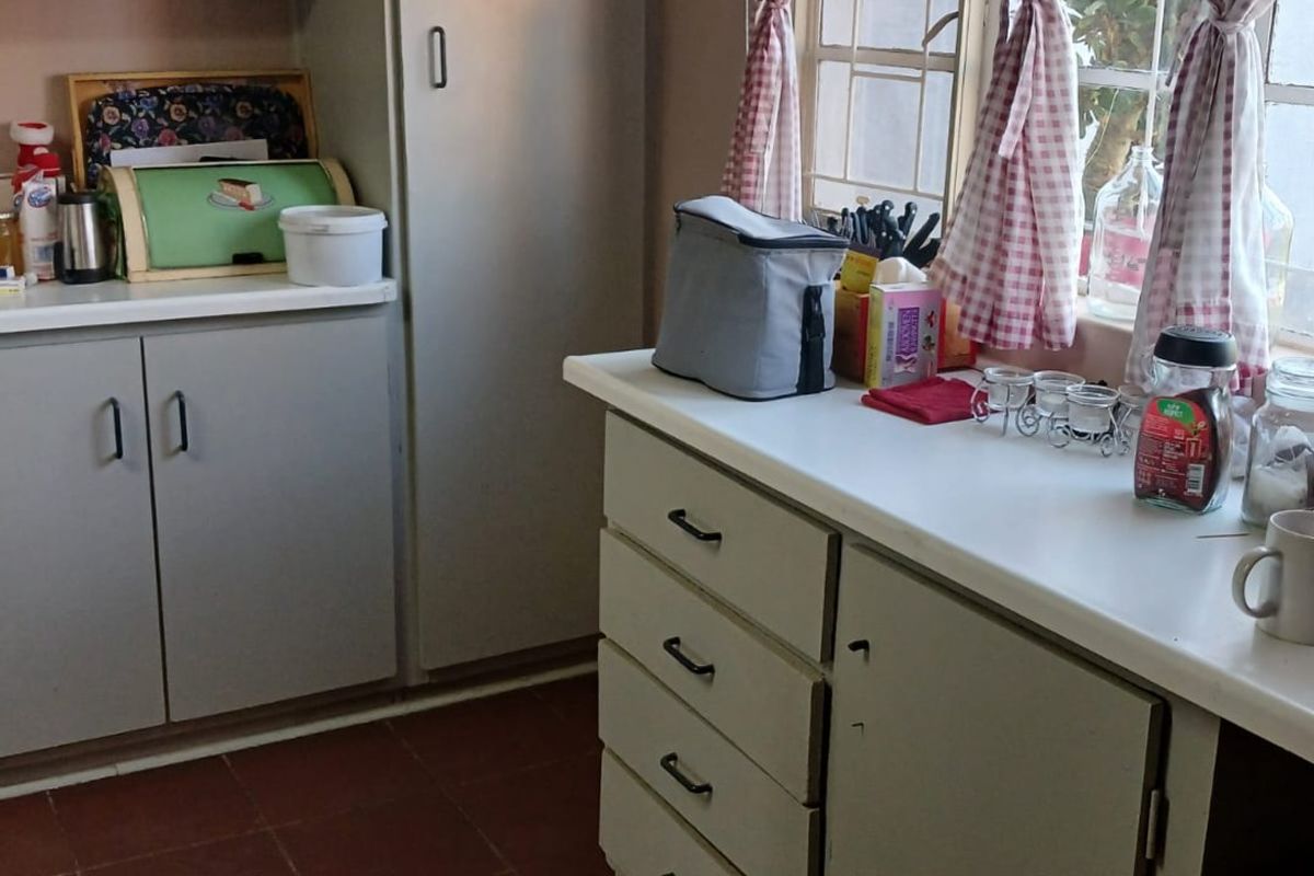 A functional kitchen featuring built-in cabinetry, laminate countertops, and tiled flooring, offering a dated aesthetic with potential for modern renovation.