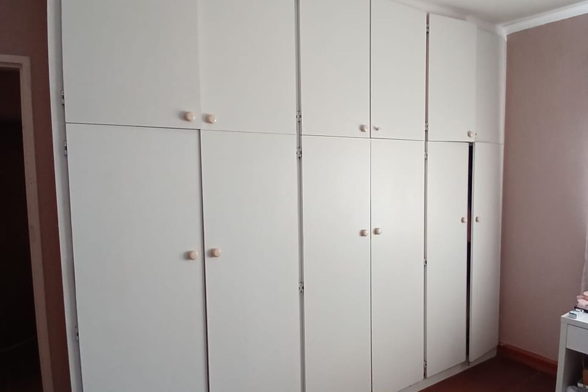 A bedroom featuring extensive floor-to-ceiling built-in cupboards and tiled flooring, providing ample storage space.
