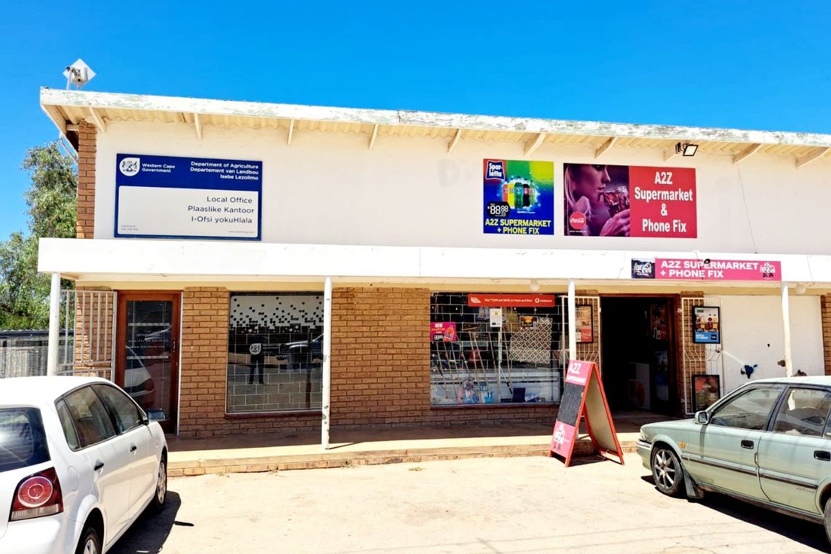 Front elevation of a commercial building featuring brick facade, covered walkway, and signage for a supermarket and local government office.