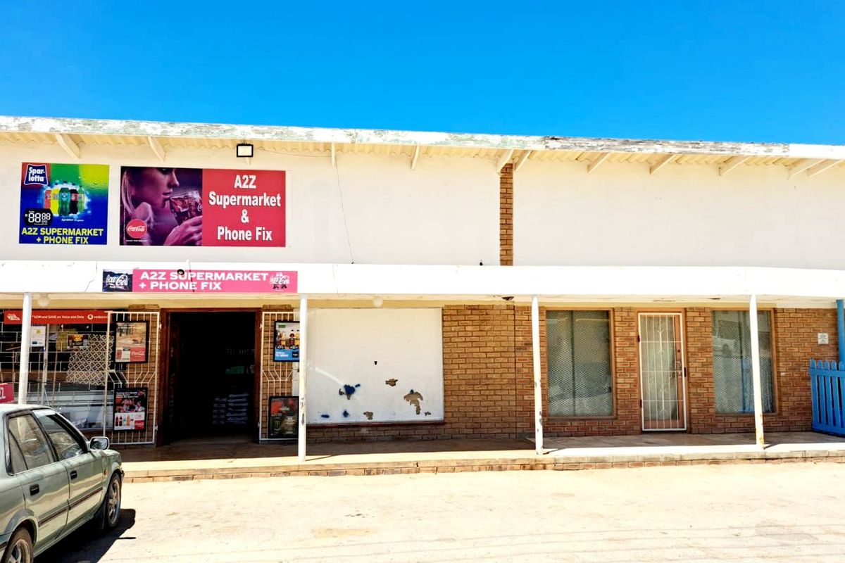 Front elevation of a commercial retail building featuring a covered walkway, brick facade, and prominent signage for a supermarket and phone repair shop.