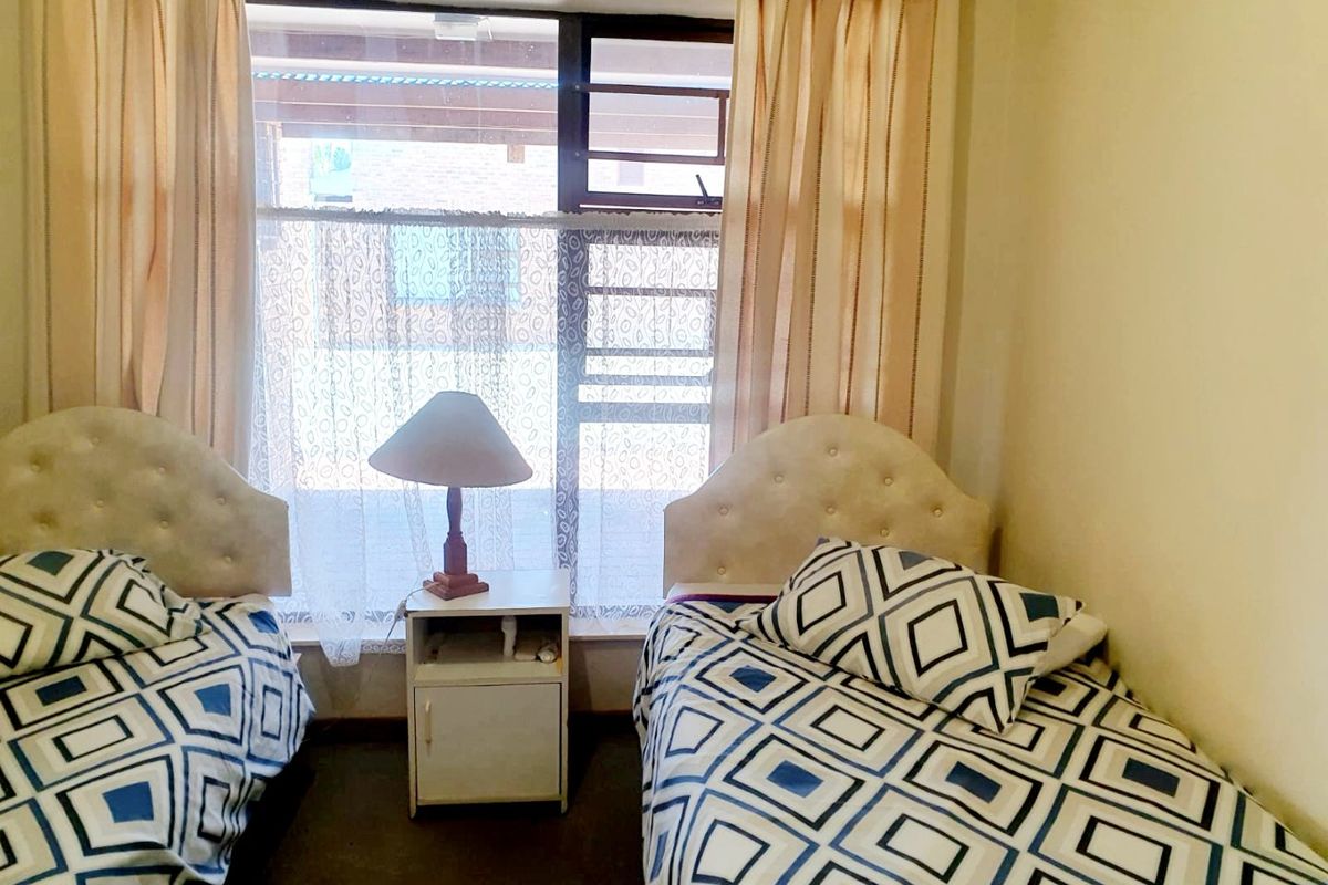 A compact bedroom featuring a large window with aluminium frames, providing natural light to the space.