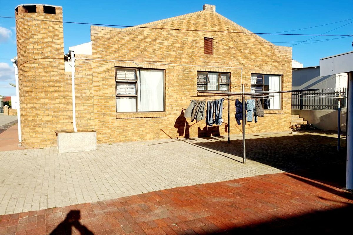 Rear exterior view of the apartment building featuring a face brick facade, paved courtyard area, and chimney stack.
