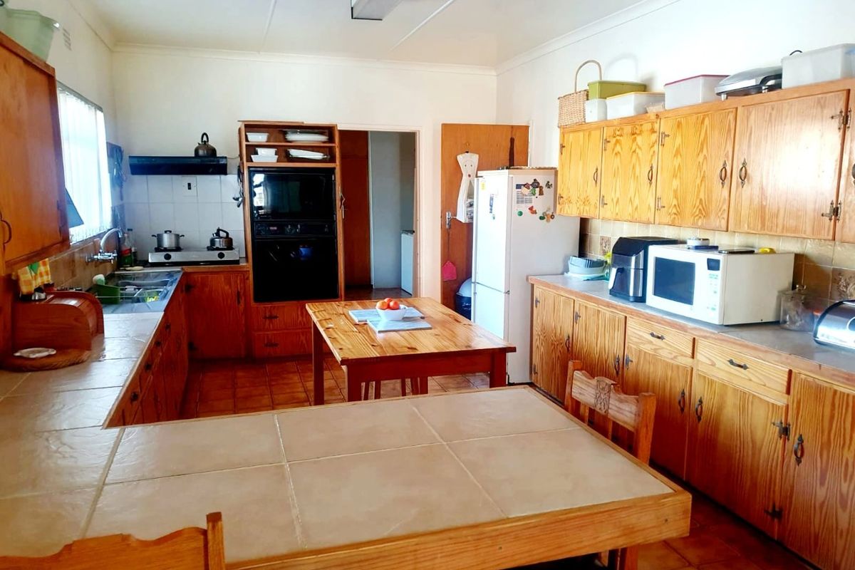 A functional kitchen featuring extensive wooden cabinetry, tiled countertops, built-in oven, and a double sink, offering a traditional layout with ample storage space.