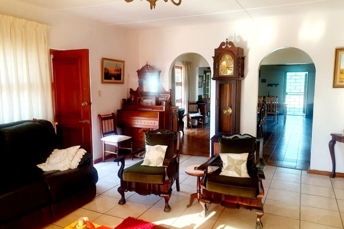 A traditional living room featuring tiled flooring and distinctive arched doorways leading to adjacent living spaces.