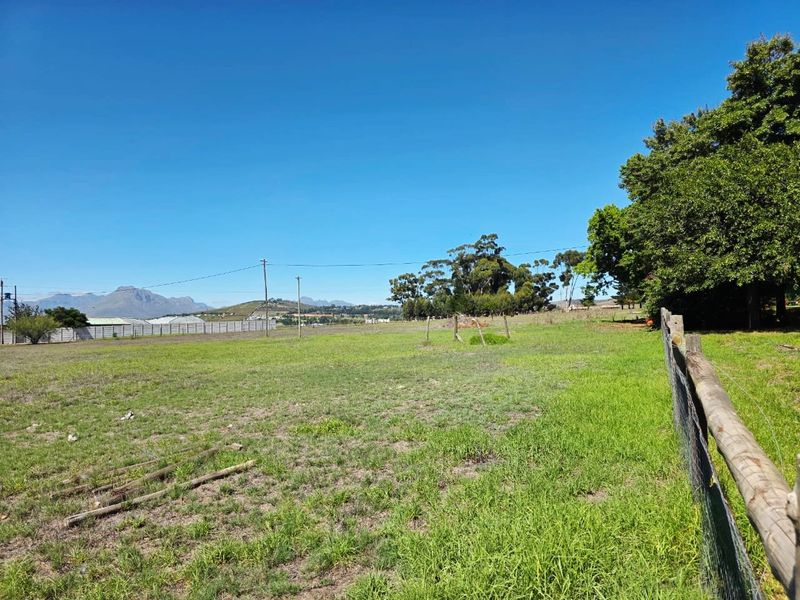 Expansive open farm land featuring a wire fence boundary and scenic mountain views in the distance.