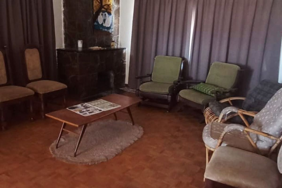 A living room featuring classic parquet flooring and a stone fireplace, offering a traditional aesthetic with potential for modern updates.