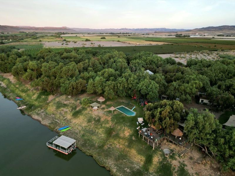 Aerial view of a riverside commercial property featuring a swimming pool, timber decking, and direct river access with a floating jetty.