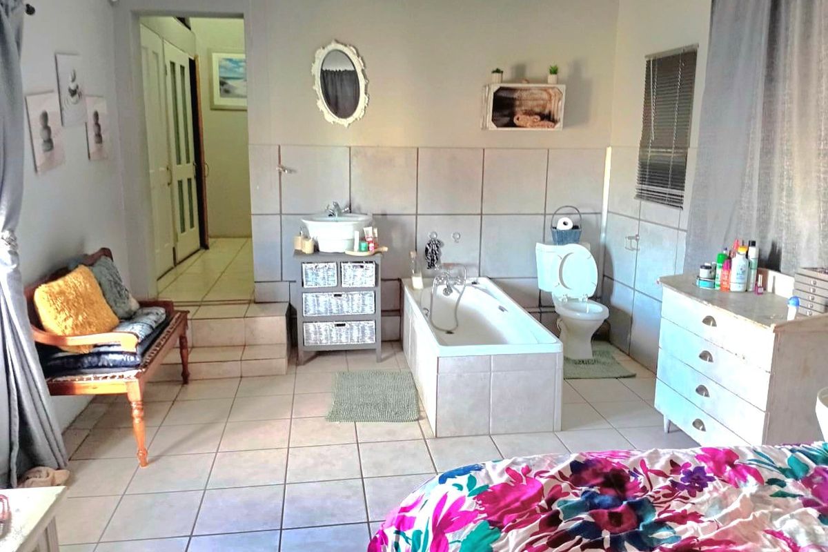A bathroom featuring tiled walls and flooring, a built-in bathtub, and a toilet, with an adjacent hallway entrance.