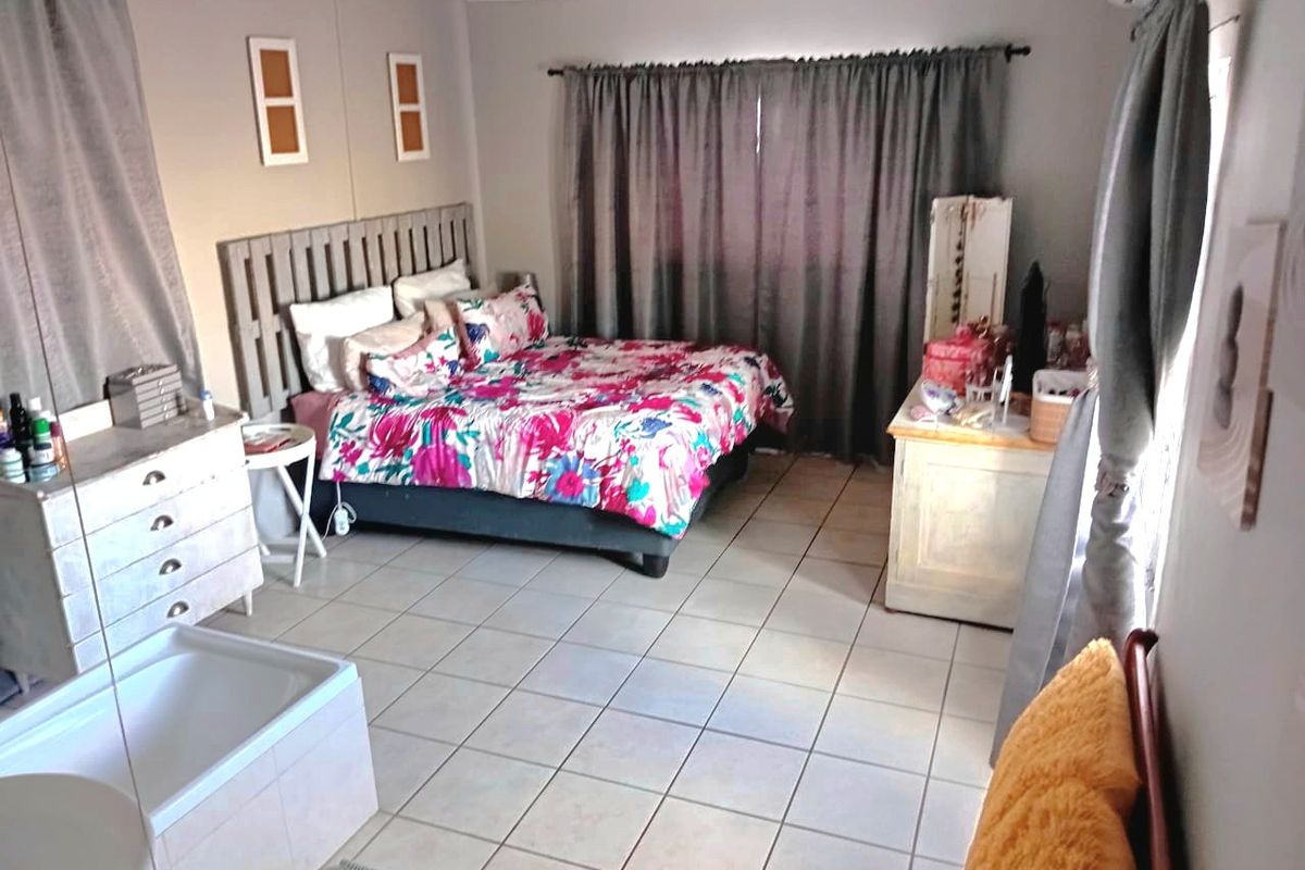 A bedroom featuring tiled flooring and a wall-mounted air conditioning unit.
