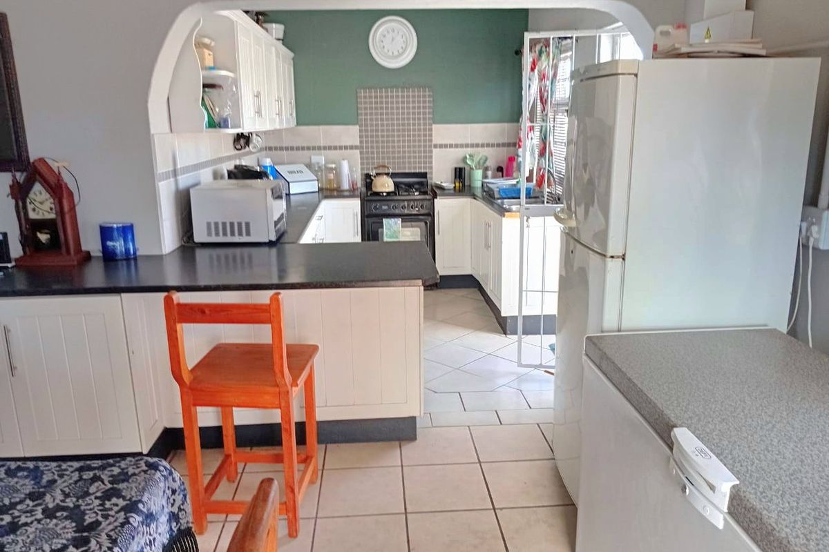 A functional kitchen featuring built-in cabinetry, a gas stove, tiled backsplash, and a breakfast bar counter, connected to the living area via an archway.