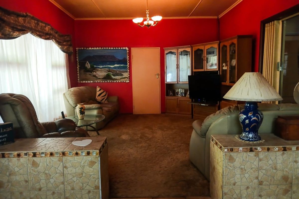 A living room featuring built-in cabinetry, tiled partition walls, and carpeted flooring, offering a traditional layout with potential for modern updates.