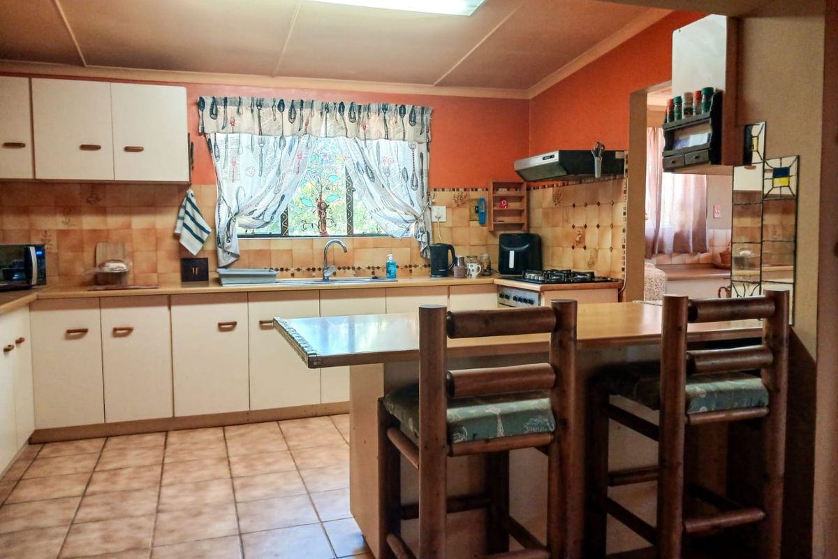 A functional kitchen featuring built-in cabinetry, a central island, gas hob with extractor, and tiled finishes throughout.