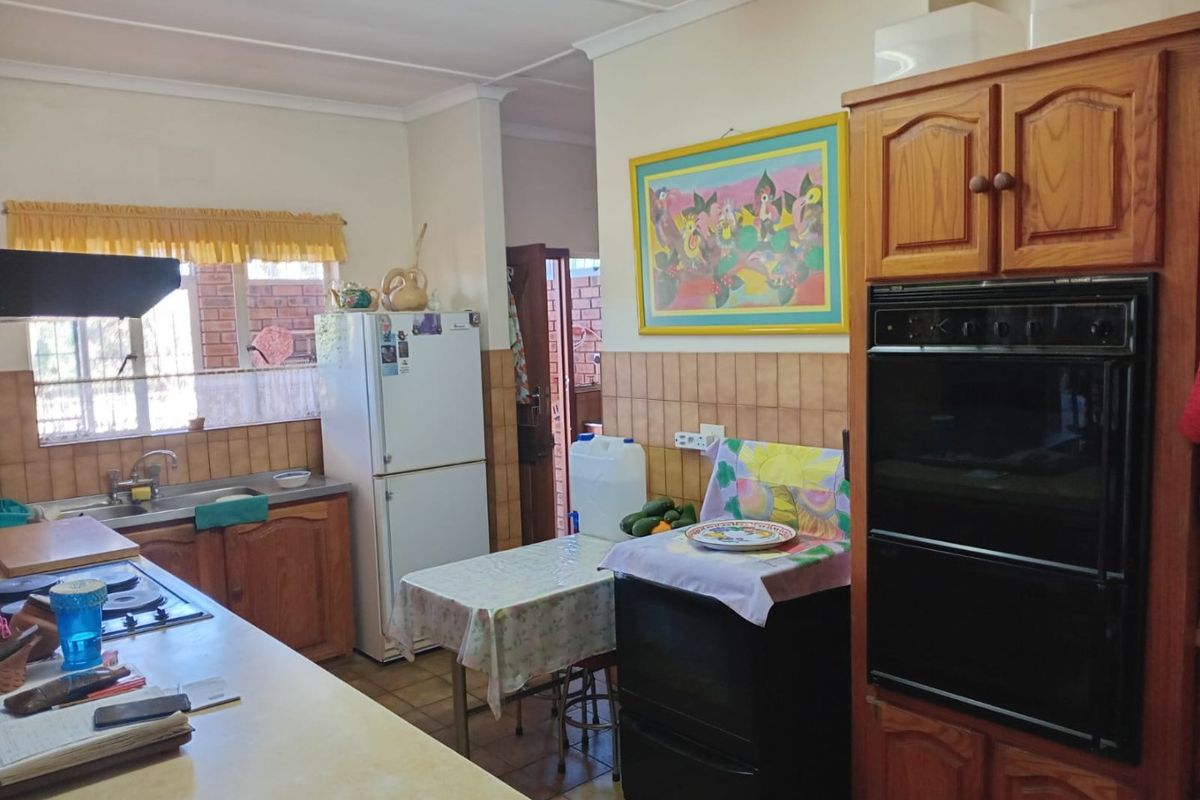 A functional kitchen featuring wooden cabinetry, a built-in double oven, hob, extractor fan, and tiled splashbacks with a double sink.