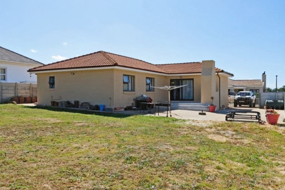 Rear view of the house featuring a tiled roof, concrete patio area, and sliding glass doors leading into the living space.