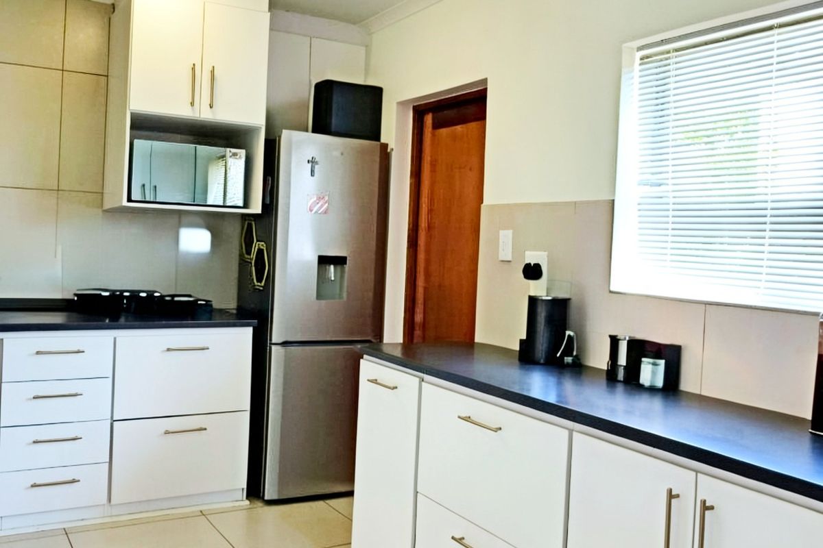 A functional kitchen featuring white cabinetry, dark countertops, tiled backsplash, and tiled flooring, offering a clean and practical workspace.