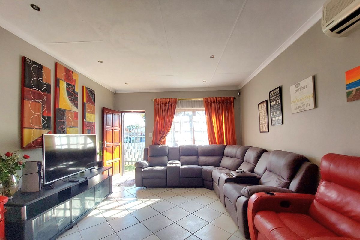 A living room featuring tiled flooring, recessed downlighting, and a wall-mounted air conditioning unit, with direct access to the exterior.