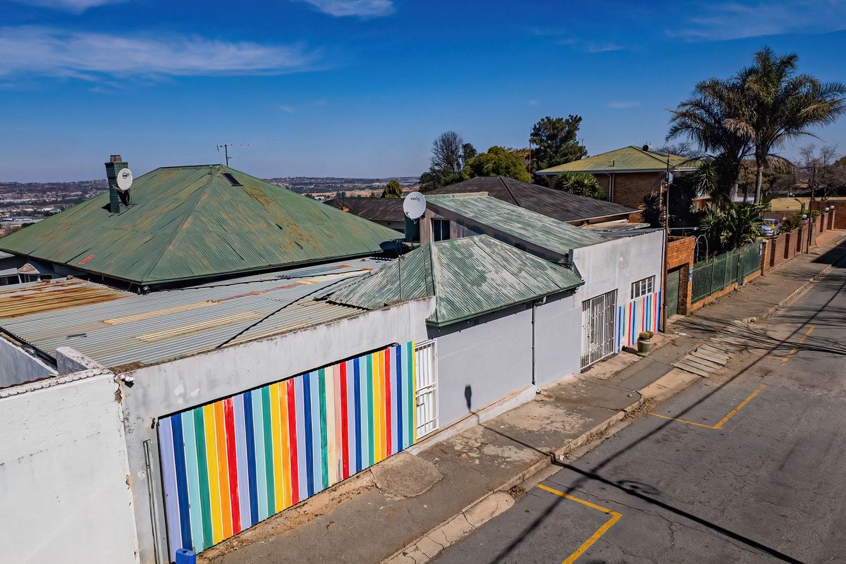 Aerial view of the property exterior showing the roof structure, boundary walls, and street-facing facade with colorful decorative accents.