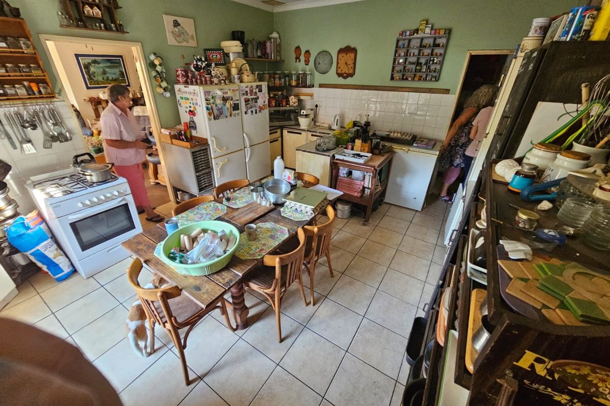 A functional farm-style kitchen featuring tiled flooring, a gas stove, and ample cabinetry, offering a traditional layout ready for modernization.