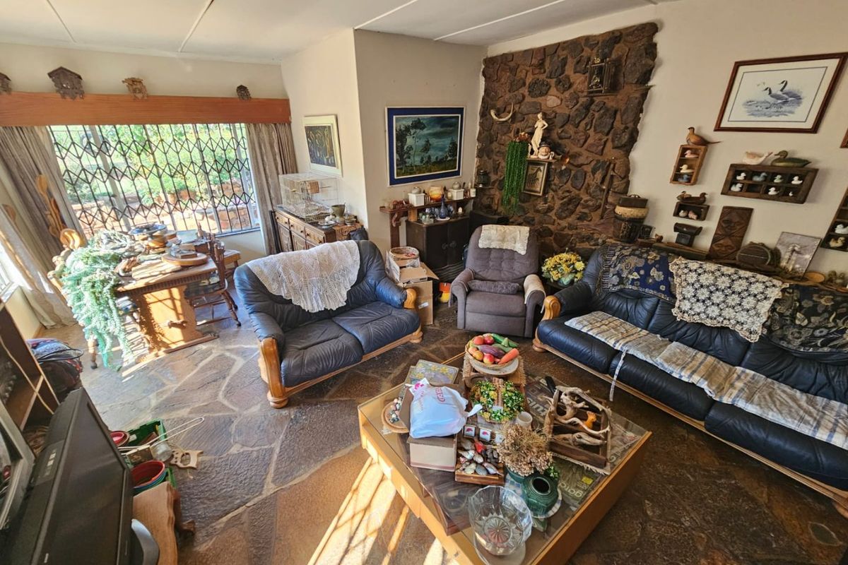 Living room featuring a rustic stone feature wall and natural stone flooring, with large windows fitted with security bars.