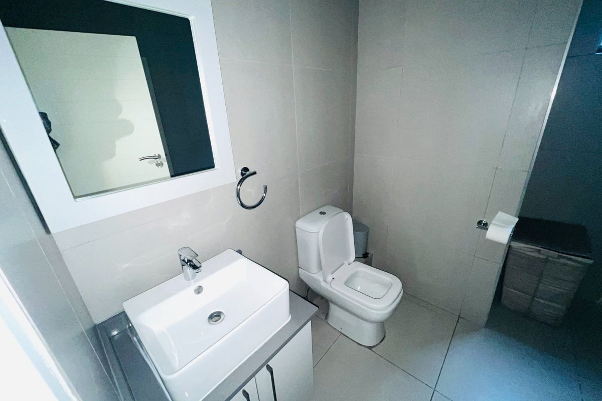 A clean, modern bathroom featuring a vessel sink vanity, wall-mounted mirror, and neutral tiled finishes throughout.