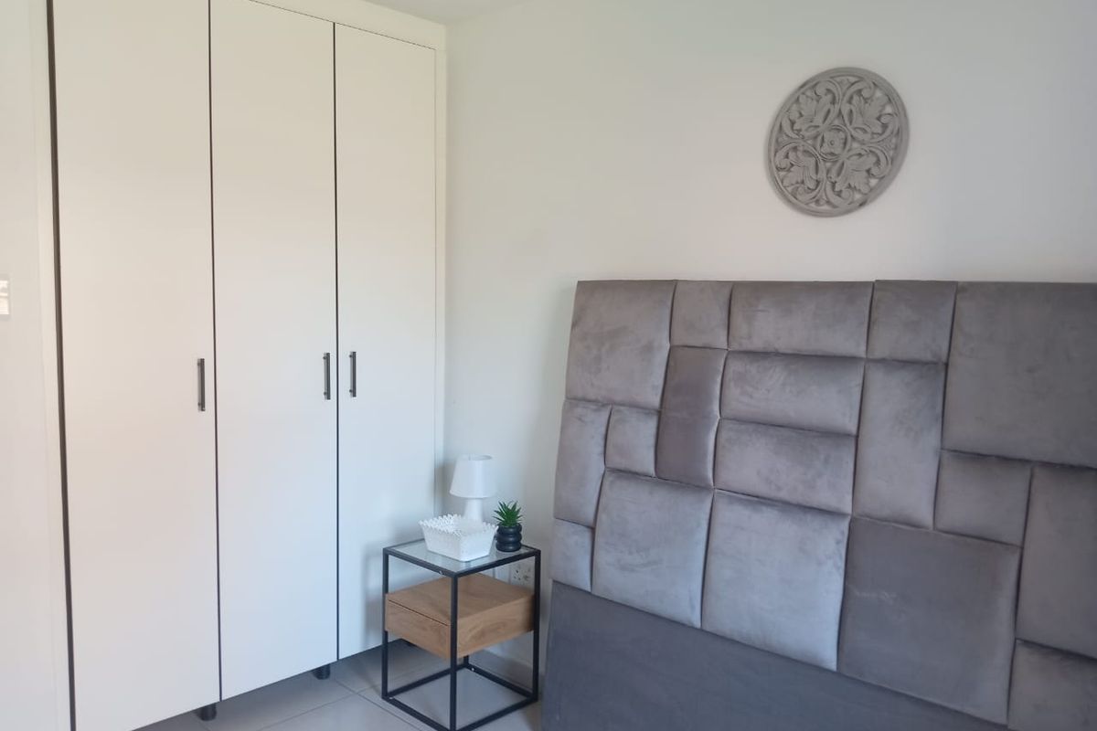 A clean and well-maintained bedroom featuring a large built-in wardrobe and neutral tiled flooring.