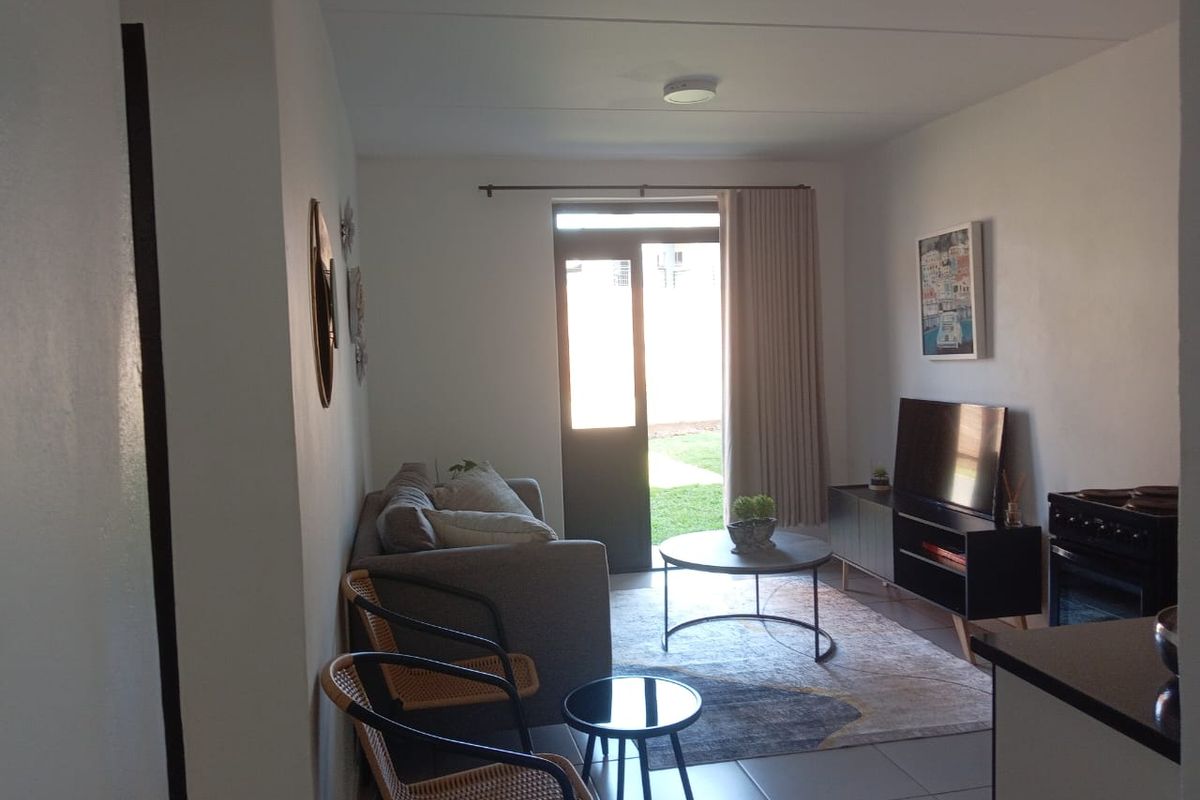 An open-plan living area featuring tiled flooring and a sliding glass door providing access to the exterior.