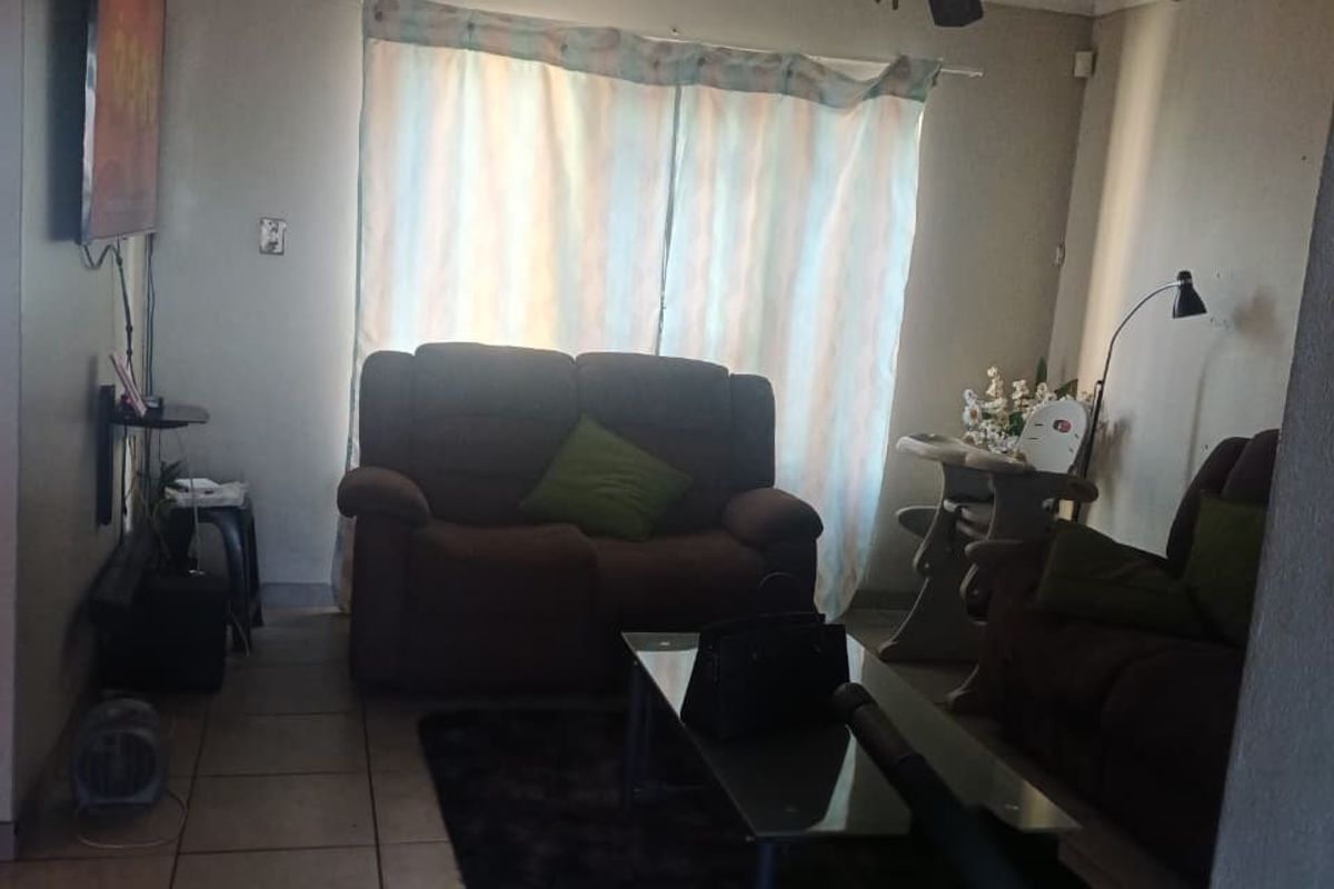 A living room featuring tiled flooring, a ceiling fan, and coved cornicing, providing a functional space for relaxation.