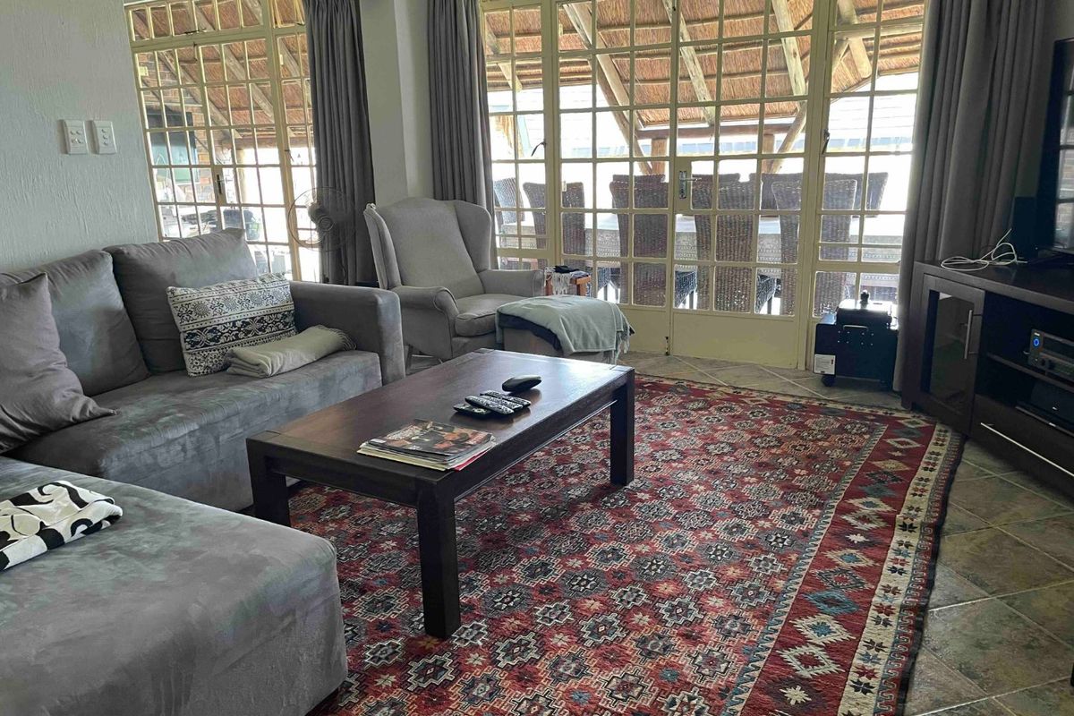 A comfortable living room featuring tiled flooring and large glass-paned french doors that provide natural light and access to the outdoor area.