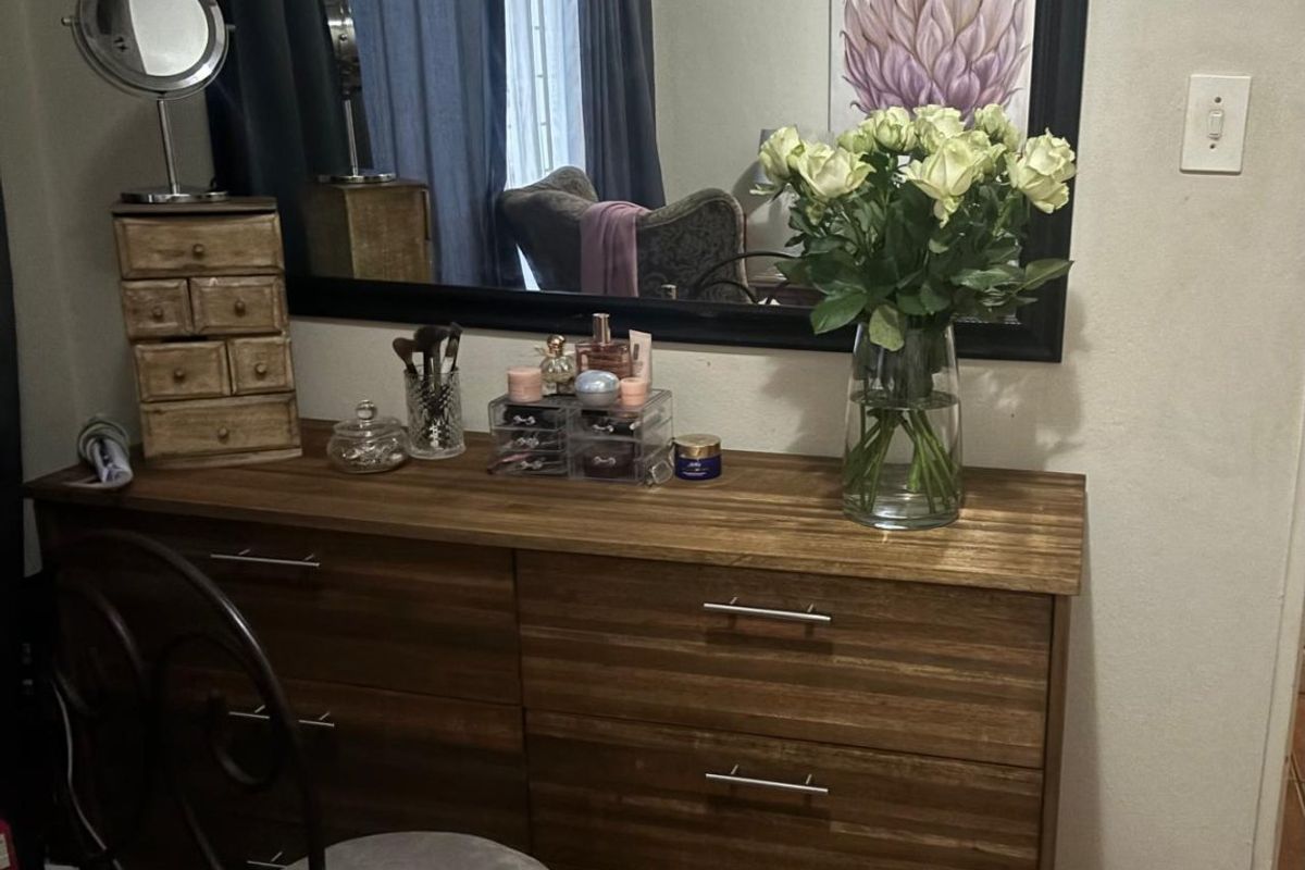 A bedroom area featuring a large wall-mounted mirror above a wooden dresser unit.