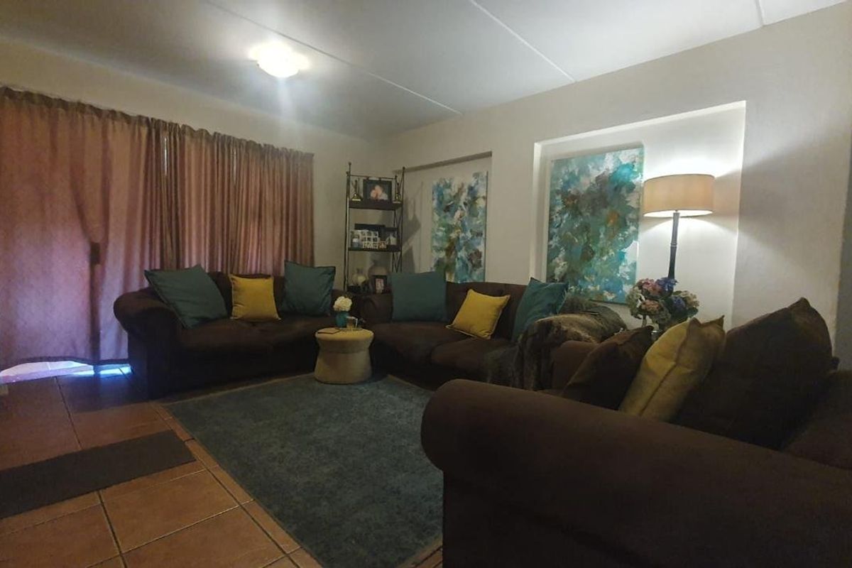 A comfortable living room featuring tiled flooring, a recessed wall niche, and a sliding glass door providing access to the outdoor area.
