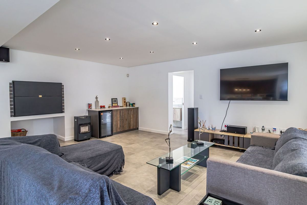 Spacious living room featuring modern tiled flooring, recessed downlighting, built-in cabinetry, and a wall-mounted television setup.
