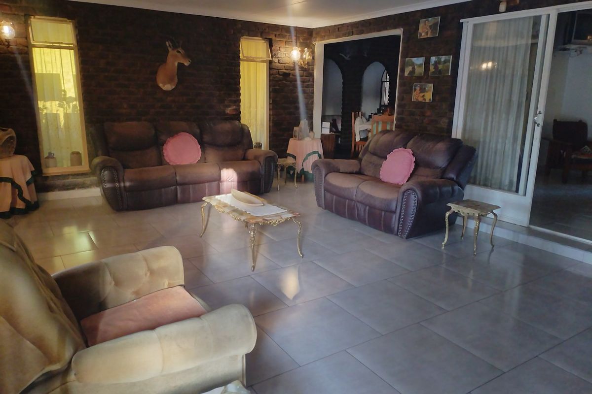 Spacious living room featuring exposed brick walls, large format floor tiles, and direct access to an adjoining area through a sliding glass door.