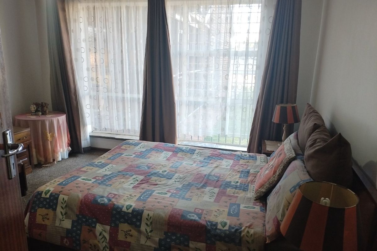 A bedroom featuring a large window with curtains and carpeted flooring.