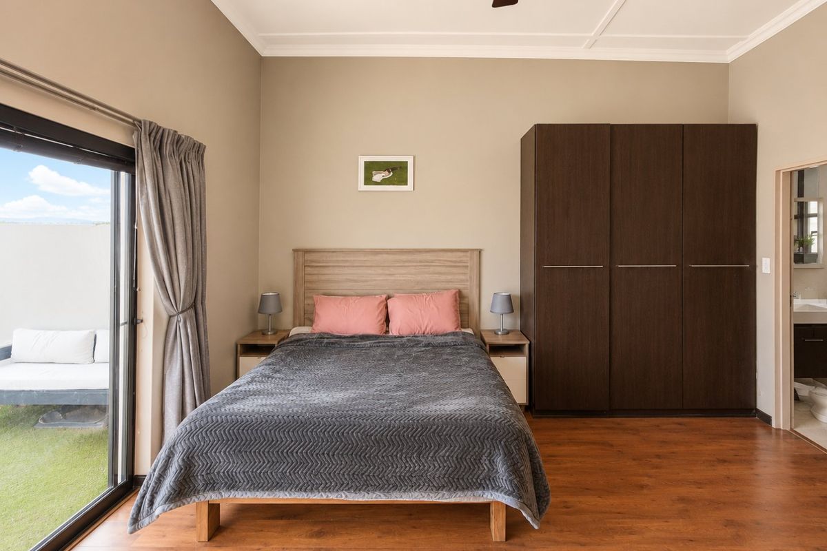 A well-maintained bedroom featuring laminate flooring, a built-in wardrobe, and a sliding glass door providing access to an outdoor area.