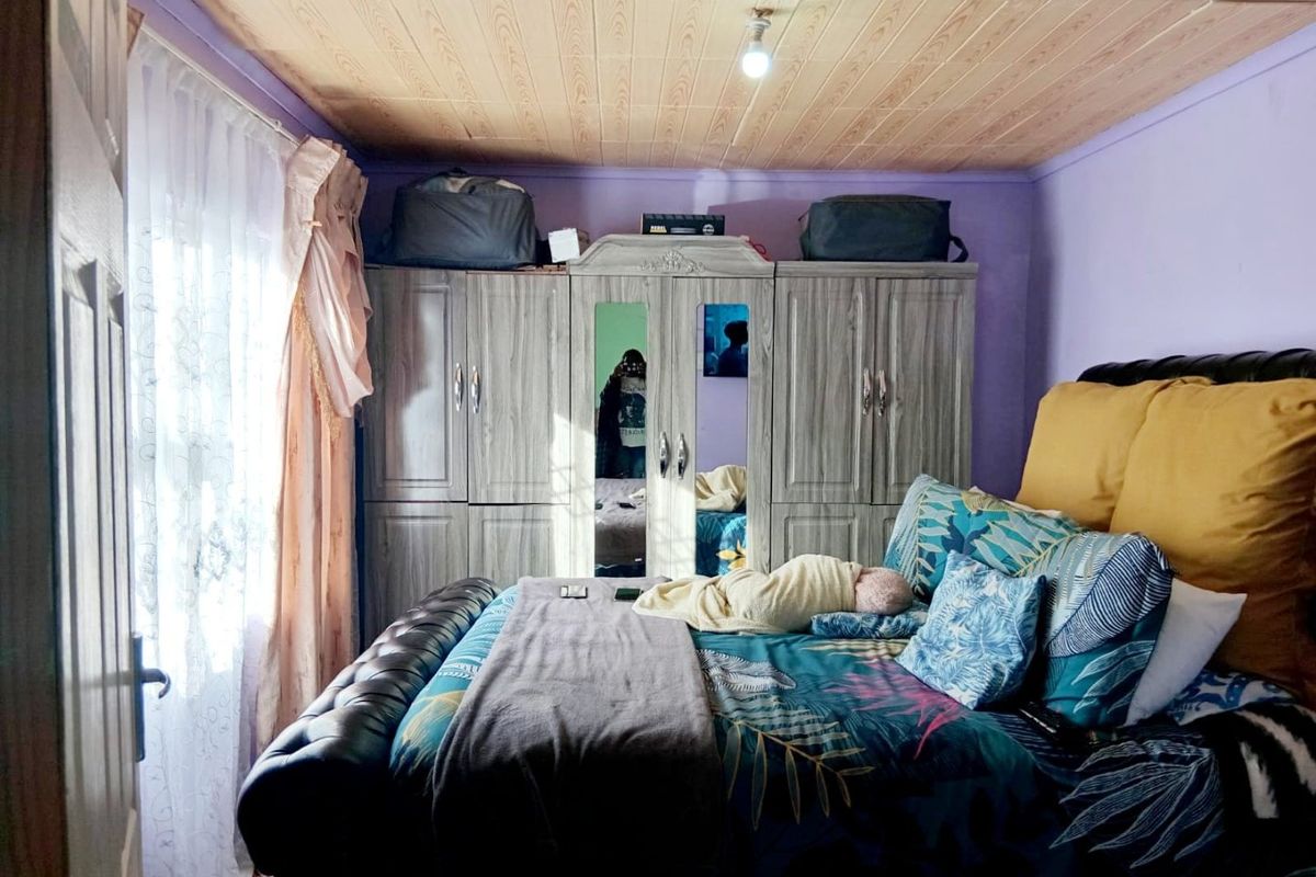 A bedroom featuring a built-in wardrobe and a timber-paneled ceiling, providing a functional sleeping space.