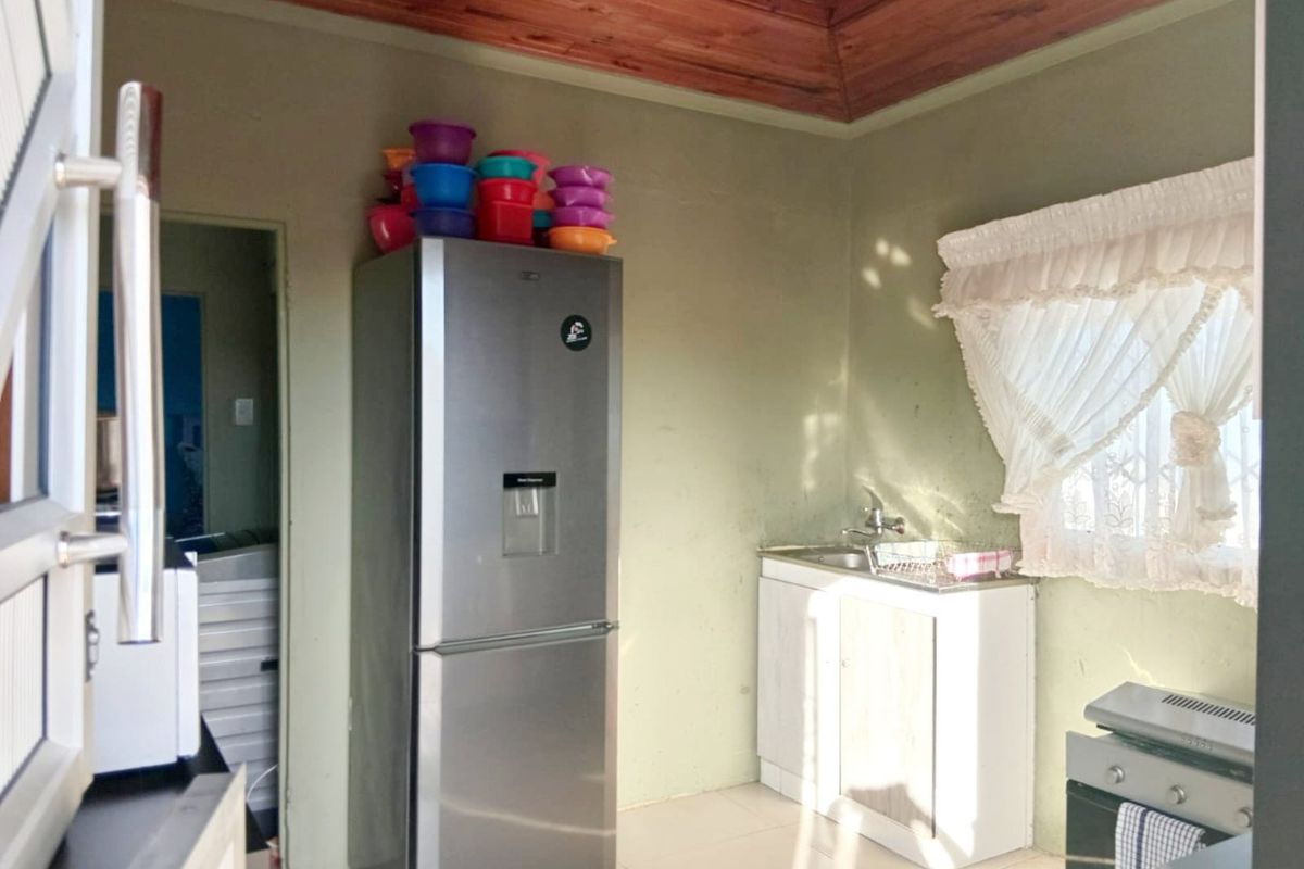 A compact kitchen area featuring a stainless steel sink, built-in cabinetry, and a distinctive timber ceiling, offering potential for modernization.