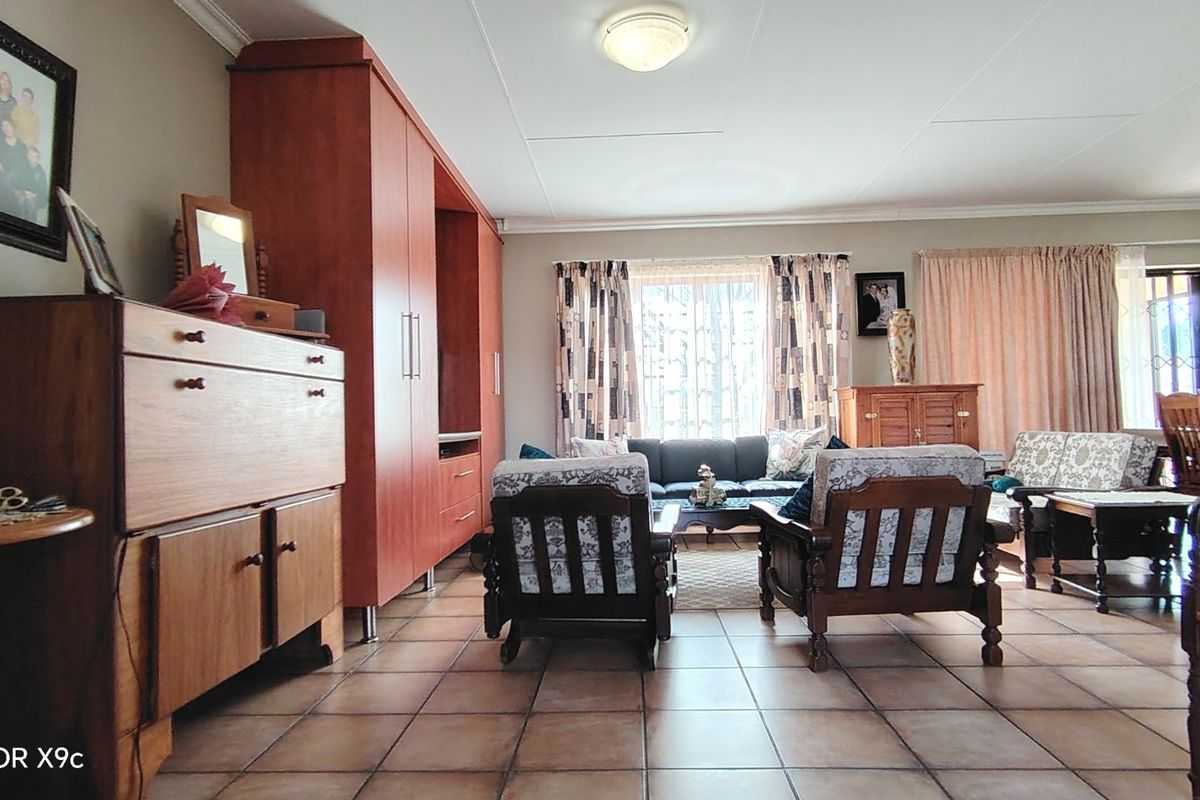 Spacious living room featuring tiled flooring, built-in cabinetry, and natural light through large windows with security gates.
