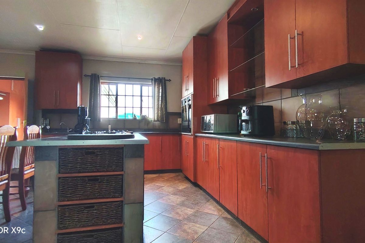 A functional kitchen featuring warm-toned built-in cabinetry, a central island, tiled flooring, and integrated oven, offering a practical layout for meal preparation.