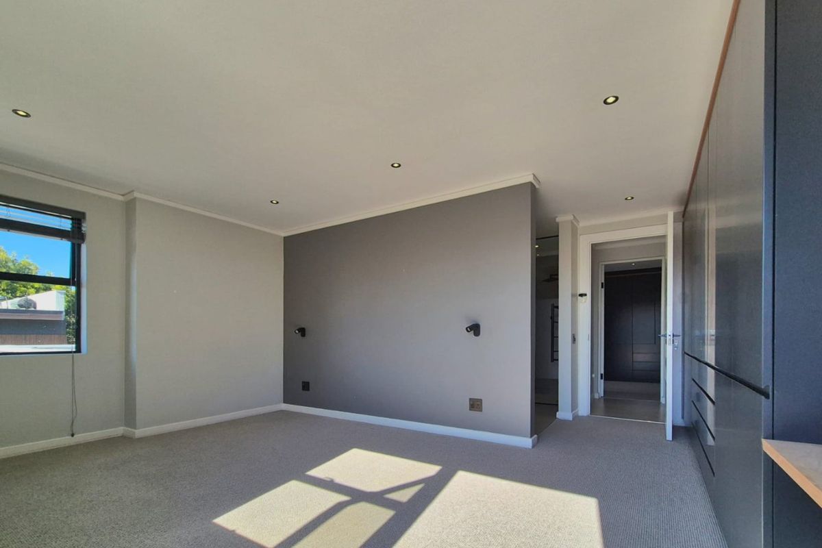Spacious bedroom featuring neutral carpeting, recessed downlighting, and extensive built-in cabinetry, offering a clean and modern living space.