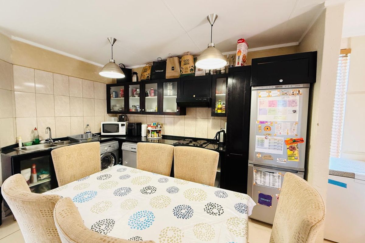 A functional kitchen featuring dark cabinetry, black granite countertops, a tiled backsplash, and integrated appliances, providing a practical workspace for daily cooking and dining.