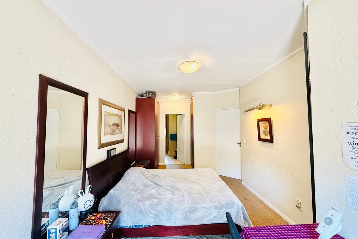 A functional bedroom featuring built-in cupboards, neutral wall finishes, and direct access to an adjoining bathroom.