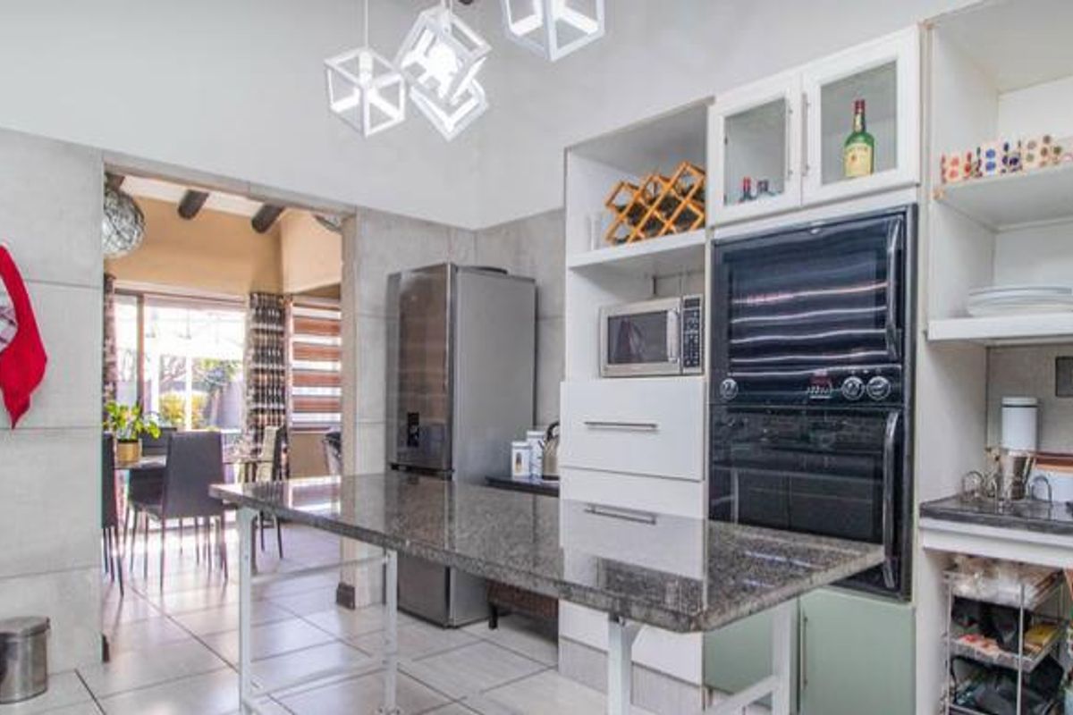 Modern kitchen featuring granite countertops, built-in oven and microwave, and ample cabinetry, flowing into an adjacent dining area.
